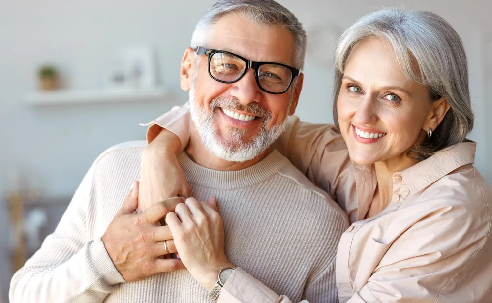 Happy Mature Couple Showing Bright, Healthy Smiles – Cosmetic Dentistry Buckhead GA A joyful older couple embraces warmly, both displaying healthy, radiant smiles that reflect confidence and excellent dental care – Cosmetic Dentistry Buckhead GA.
