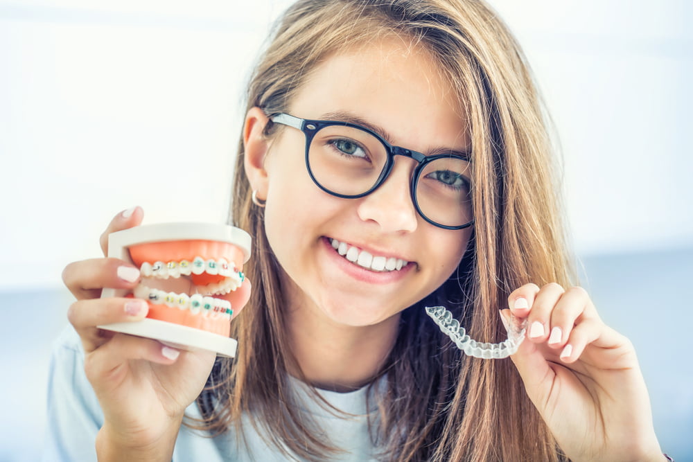 Woman holding a teeth model and a invisalign