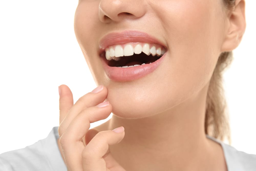 A dentist explains a dental procedure using a model of teeth while the patient smiles in the background - Dentist Atlanta