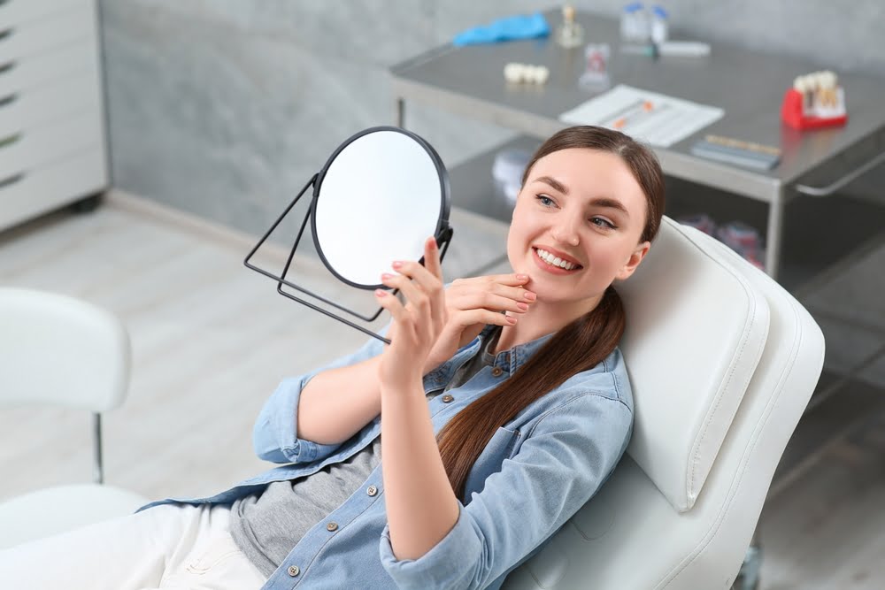 Woman checking her teeth in the mirror Dental Veneers