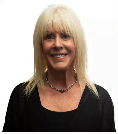 A woman with blonde hair smiling, wearing a black top and a silver necklace - Dentist Atlanta A woman with blonde hair smiling, wearing a black top and a silver necklace - Dentist Atlanta