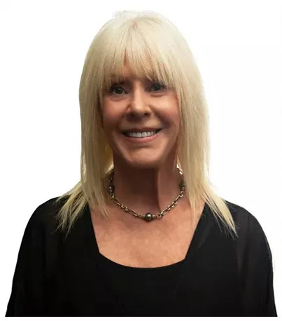A woman with blonde hair smiling, wearing a black top and a silver necklace - Cosmetic Dentistry Buckhead GA A woman with blonde hair smiling, wearing a black top and a silver necklace - Cosmetic Dentistry Buckhead GA